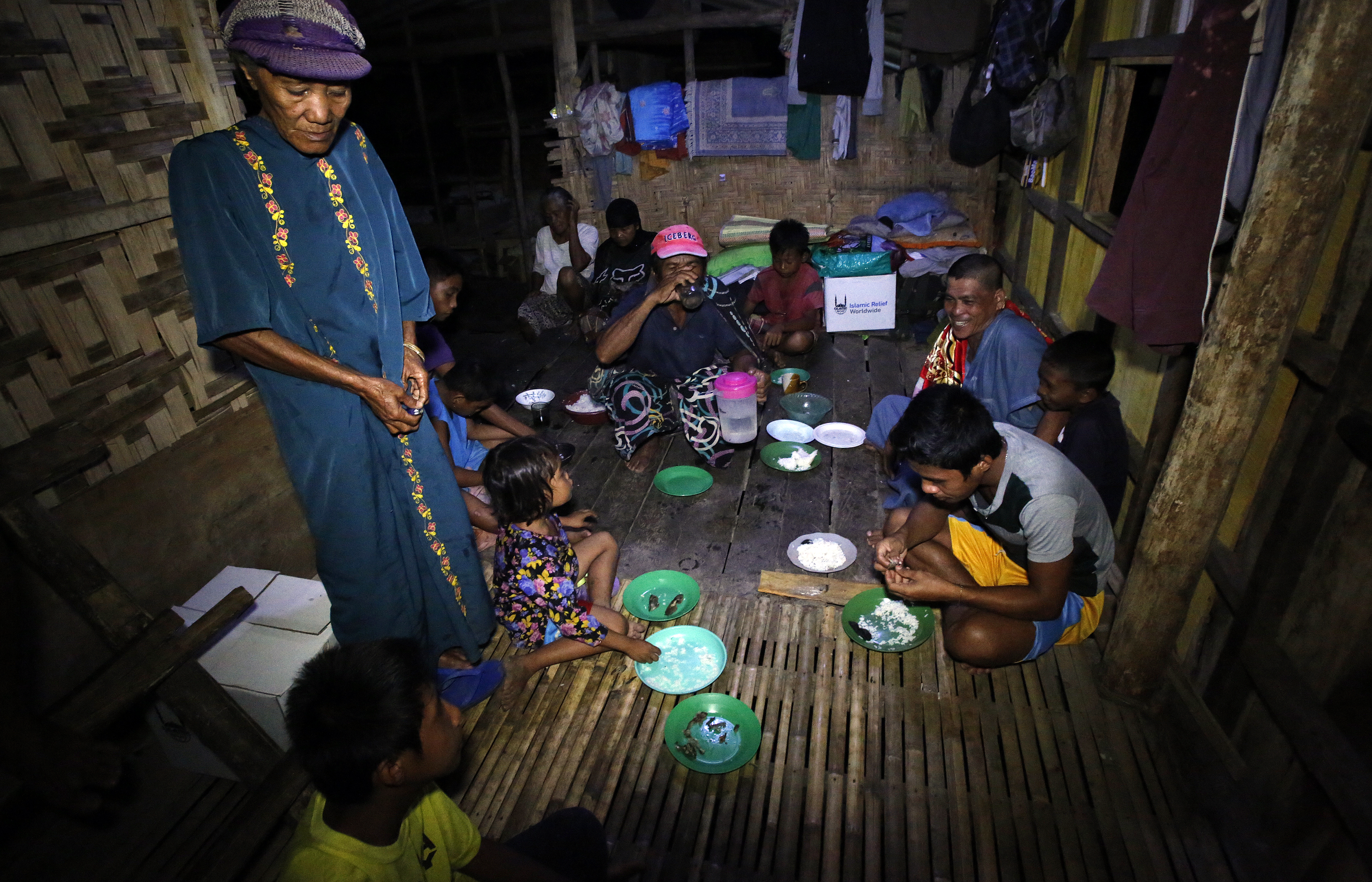 Imam Guiamed Nur sits with his neighbours in their community hut to break fast together.
